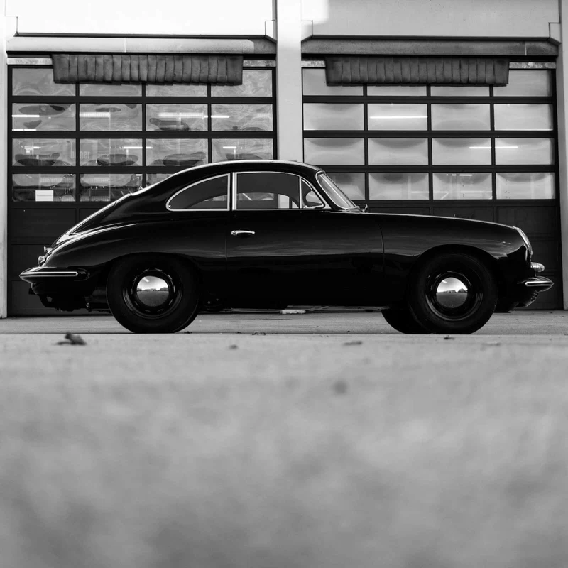 Aluminiumbild Klassisches Auto vor Werkstattgebäude Quadrat
