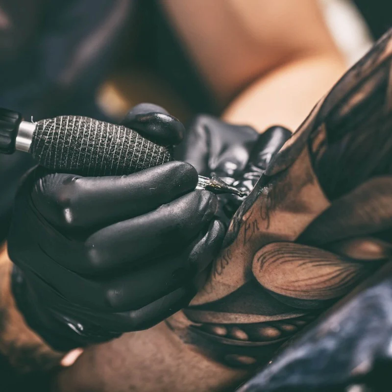 Spannrahmenbild Künstler beim Tätowieren eines Tattoo Quadrat